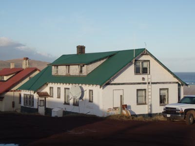 Photo of white cottage with green roof.